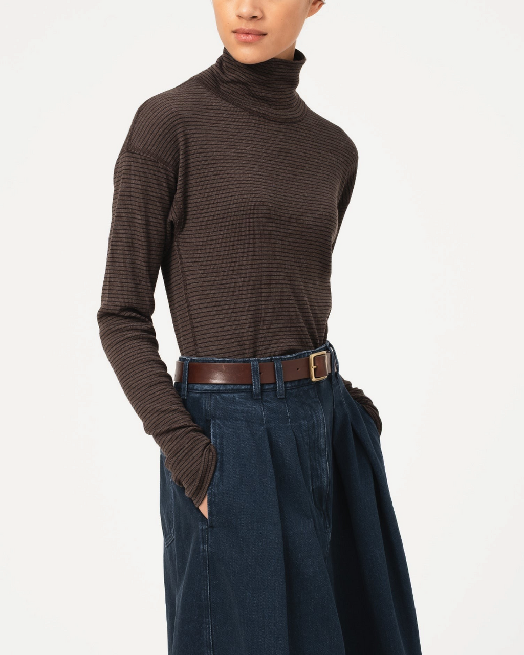Modèle portant un pull à col roulé Merci Paris Girls Of Dust en maille côtelée marron sépia, coupe ajustée.