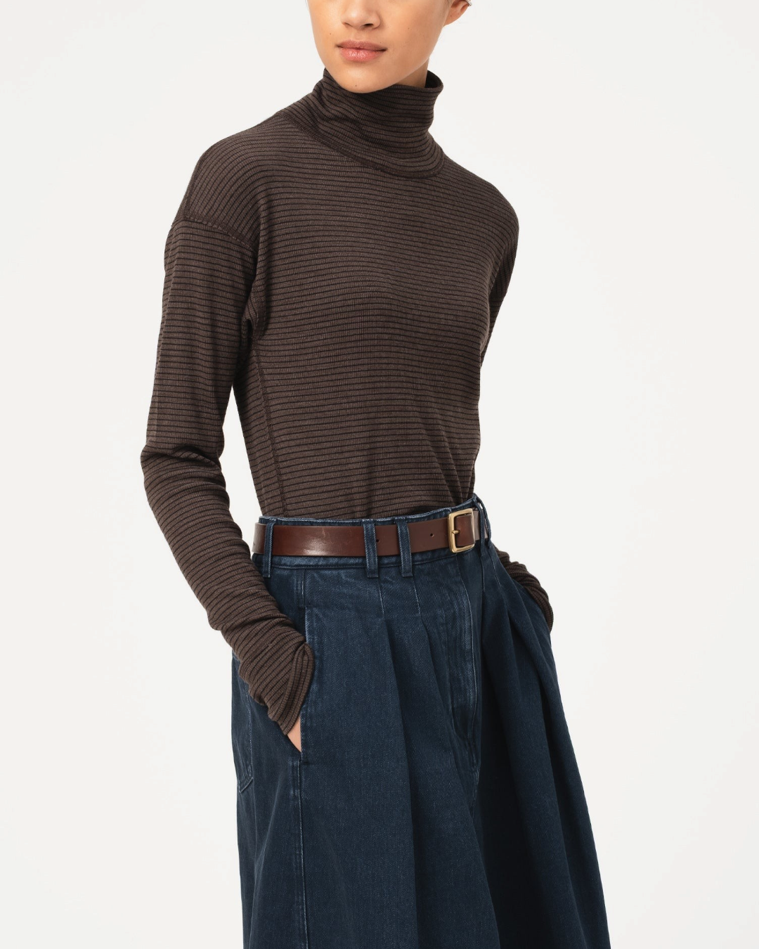 Modèle portant un pull à col roulé Merci Paris Girls Of Dust en maille côtelée marron sépia, coupe ajustée.